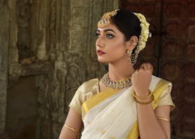 Beautiful Indian woman in traditional saree, adorned with exquisite jewelry, set against historic architecture.